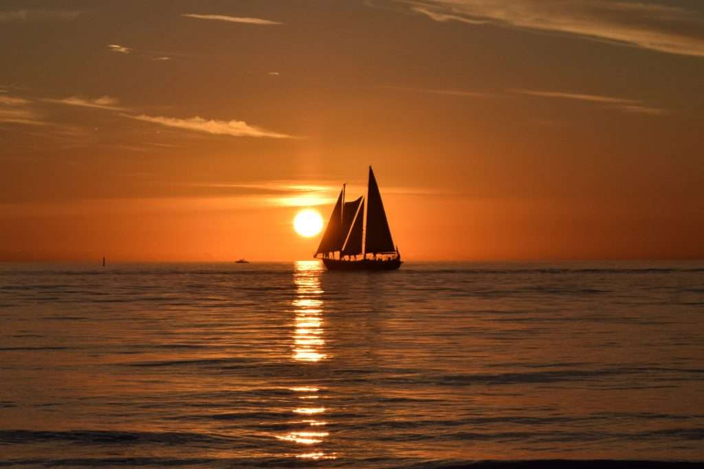 Sailboat at sunset on calm coastal waters