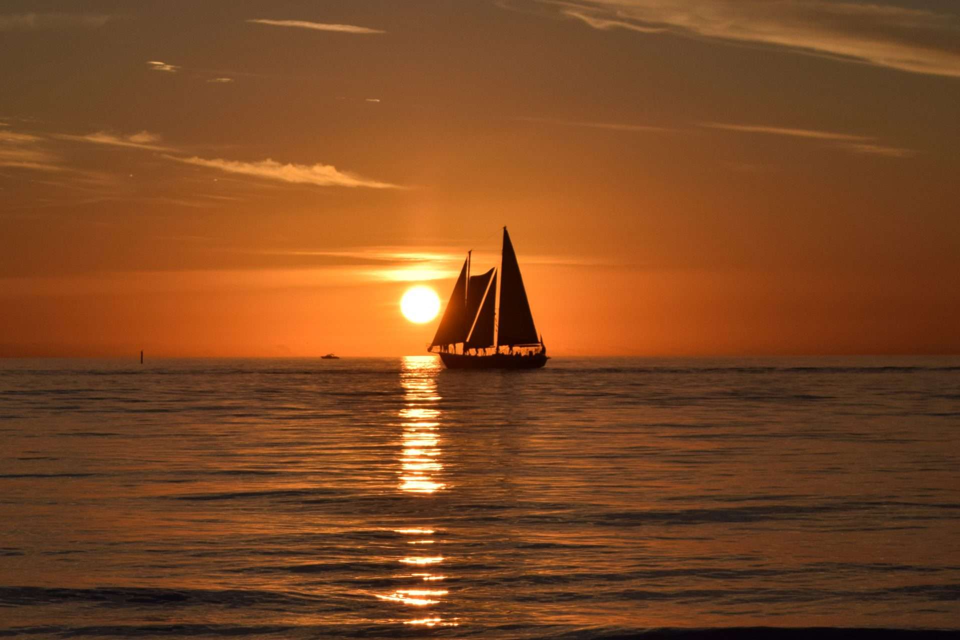 Sailboat at sunset on calm coastal waters